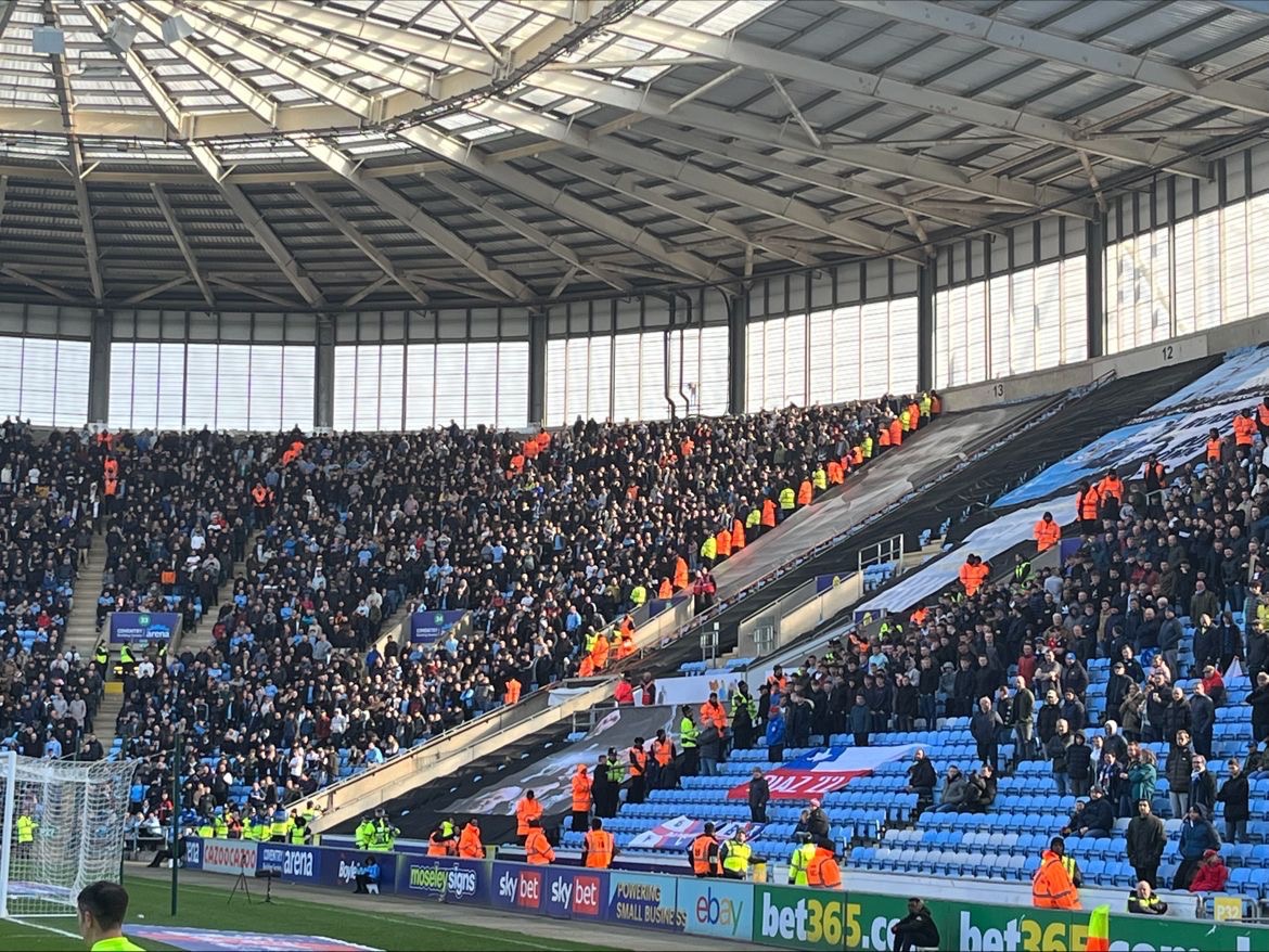 A busy stadium stand with security and event personnel positioned around the audience areas