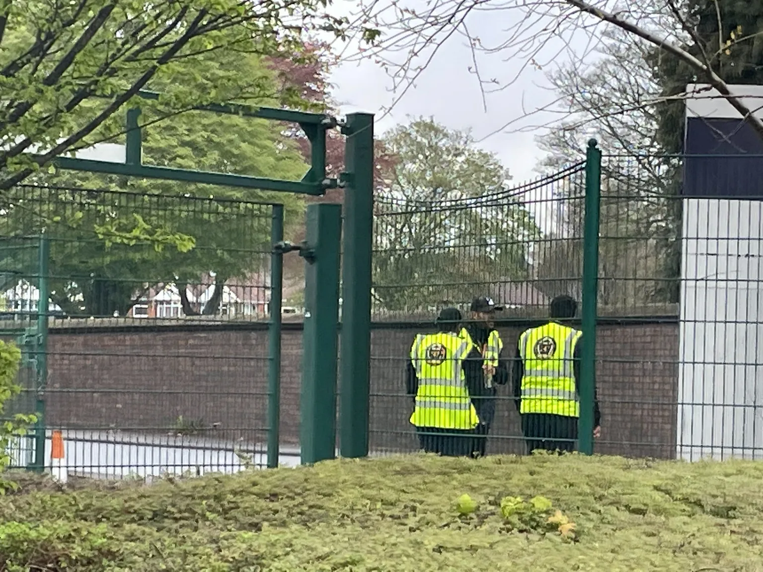 Guards 247 security officers in branded hi-vis vests beside a perimeter fence