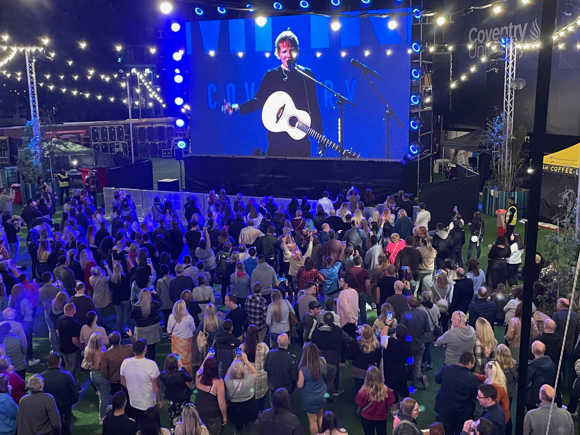 Large crowd watching the main stage screen during the Coventry live event
